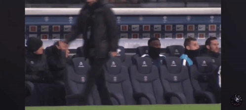 a group of soccer players sit in a stadium watching a game