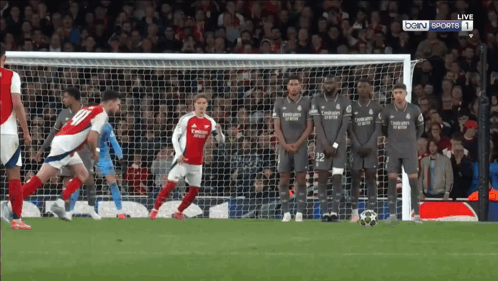 A Group Of Soccer Players Wearing Emirates Jerseys Stand In Front Of A Soccer Goal GIF