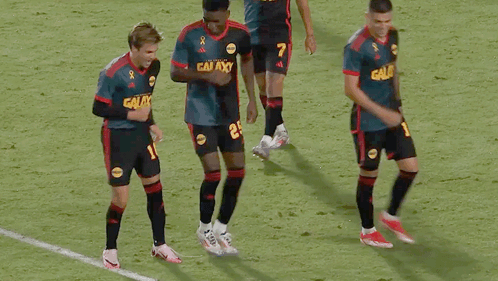A Group Of Soccer Players Wearing Galaxy Jerseys Are Dancing On The Field GIF