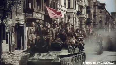 A Group Of Soldiers Are Riding On A Tank In Front Of A Building That Says Bianca GIF