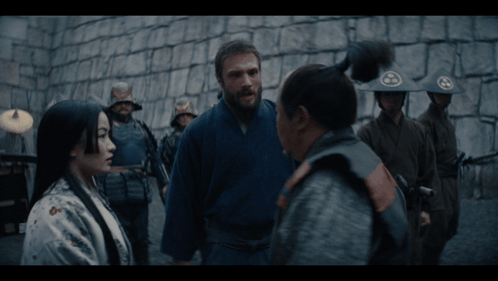 a group of soldiers are standing in front of a stone wall and talking to each other