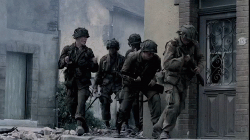 A Group Of Soldiers Are Walking Down A Street In Front Of A Building With The Number 15 On It GIF