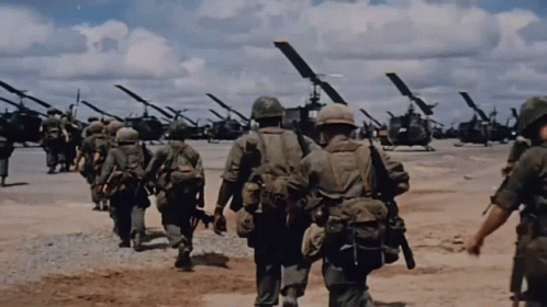 A Group Of Soldiers Are Walking In Front Of A Line Of Helicopters GIF
