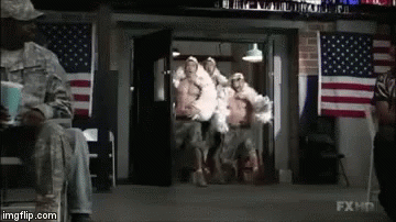 A Group Of Soldiers Are Walking Out Of A Building In Front Of American Flags . GIF