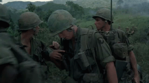 A Group Of Soldiers Wearing Green Uniforms And Helmets Are Standing In A Field GIF