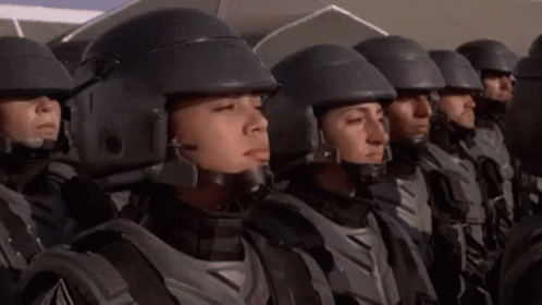 A Group Of Soldiers Wearing Helmets Are Standing In A Line . GIF