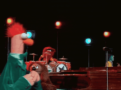 A Group Of Stuffed Animals Are On A Stage Including Beaker GIF