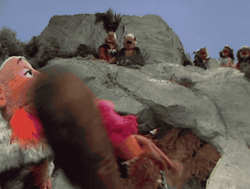 A Group Of Stuffed Animals Are Sitting On A Rocky Hillside GIF