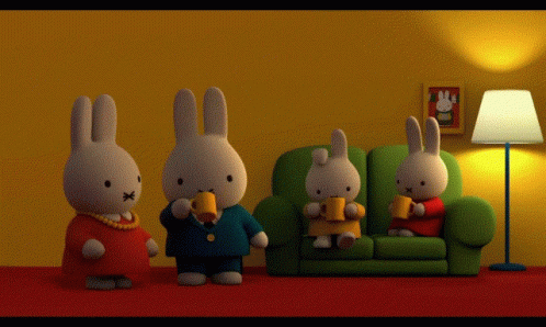 A Group Of Stuffed Rabbits Are Sitting On A Couch Drinking Coffee GIF