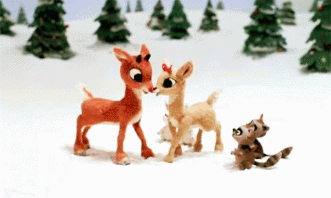 A Group Of Stuffed Reindeer Standing In The Snow GIF