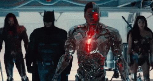 A Group Of Superheros Standing Next To Each Other In A Room . GIF