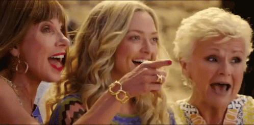A Group Of Three Women Are Laughing And Pointing At Something . GIF