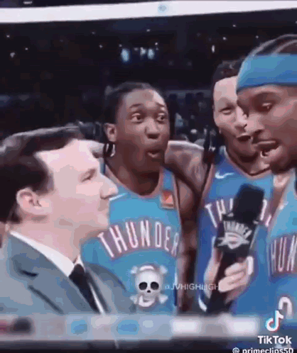 A Group Of Thunder Basketball Players Are Talking To A Man In A Suit . GIF
