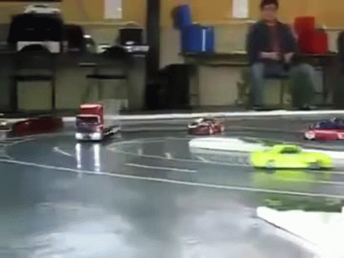 A Group Of Toy Cars Are Racing On A Track In A Room GIF