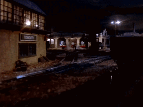 A Group Of Train Engines Are Parked In A Garage At Night GIF