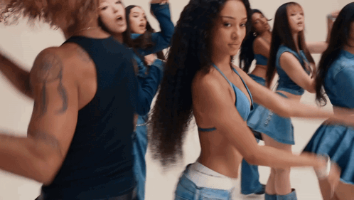 A Group Of Women Are Dancing In Blue Outfits With A Man In A Black Tank Top GIF