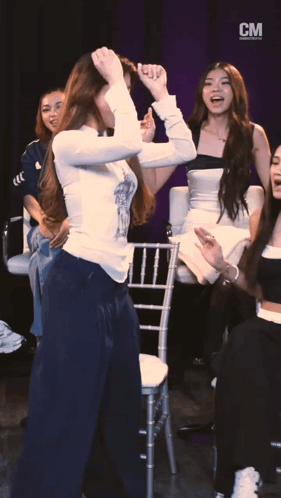 A Group Of Women Are Dancing In Front Of A Cm Banner GIF