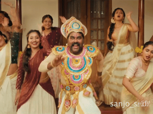 a group of women are dancing in front of a man in a costume with the name sanjo written on the bottom