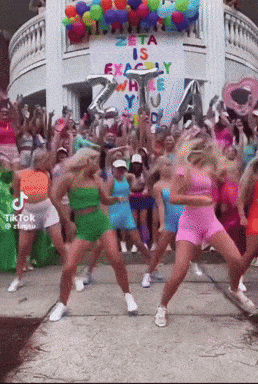 A Group Of Women Are Dancing In Front Of A Sign That Says Zeta Is Exactly Where You 'Re Going GIF