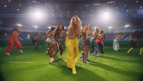 a group of women are dancing on a field in front of a crowd