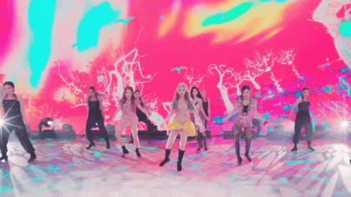 a group of women are dancing on a stage with a colorful background .