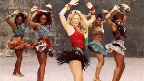 a group of women are dancing together and one of them is wearing a red tank top .
