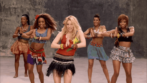 a group of women are dancing together and one of them is wearing a red top
