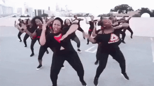 A Group Of Women Are Dancing Together On A Parking Lot . GIF