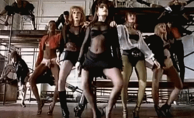 A Group Of Women Are Dancing Together On A Stage In A Room . GIF