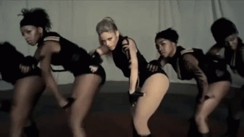A Group Of Women Are Dancing Together On A Stage In A Room . GIF