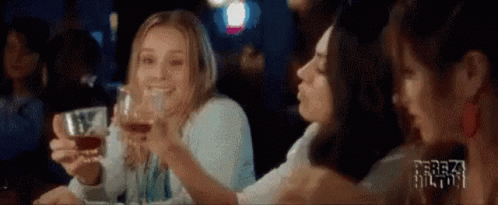 A Group Of Women Are Sitting At A Table Drinking Wine And Toasting . GIF
