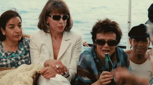 A Group Of Women Are Sitting On A Boat One Of Them Is Drinking From A Bottle GIF