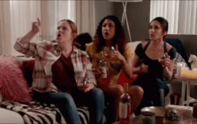 A Group Of Women Are Sitting On A Couch Drinking Wine And Watching Tv . GIF