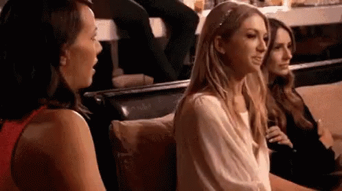 A Group Of Women Are Sitting On A Couch Talking To Each Other In A Restaurant . GIF