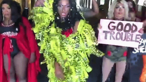 A Group Of Women Are Standing Next To Each Other Holding Signs That Say Good Trouble . GIF