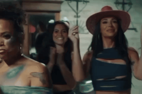 A Group Of Women Are Standing Next To Each Other In A Room . GIF