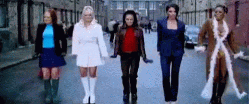 A Group Of Women Are Standing Next To Each Other On A City Street . GIF