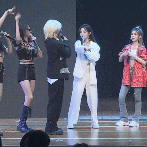 A Group Of Women Are Standing On A Stage Holding Microphones GIF