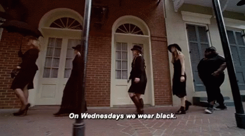 A Group Of Women Are Walking Down A Street And One Of Them Is Saying On Wednesdays We Wear Black GIF