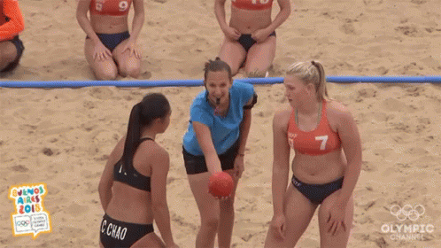 a group of women in bikinis are playing handball on the beach .