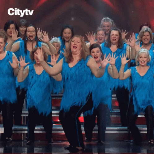 A Group Of Women In Blue Dresses Are Dancing On A Stage GIF