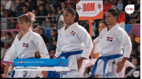 A Group Of Women In Karate Uniforms Standing In Front Of A Sign That Says Dom GIF