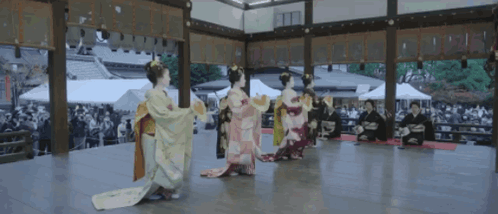 A Group Of Women In Kimonos Are Performing A Dance GIF