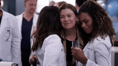 A Group Of Women In Lab Coats Hugging Each Other While Holding A Glass Of Champagne . GIF