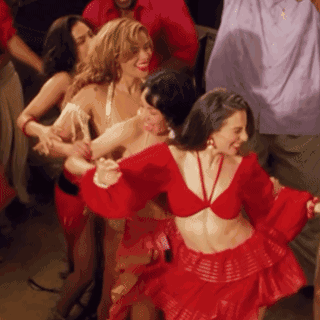 A Group Of Women In Red Dresses Are Dancing In A Crowd GIF