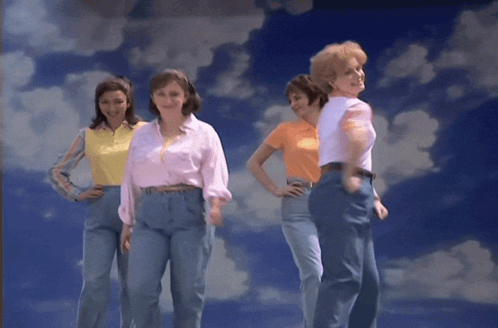 A Group Of Women Standing In Front Of A Blue Sky With Clouds GIF