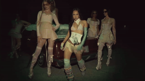 A Group Of Women Standing In Front Of A Car In A Dark Room GIF