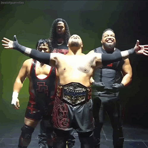 A Group Of Wrestlers Are Posing For A Photo And One Of Them Has A Belt That Says Heavyweight GIF