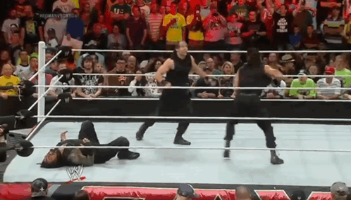 A Group Of Wrestlers Are Standing In A Ring With A Crowd Watching . GIF