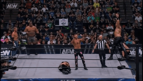 a group of wrestlers are standing in a ring with a sign that says hey on it